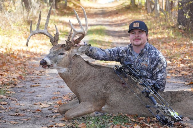 Hunter poses with his bow and a large drop tine buck with 13 points.