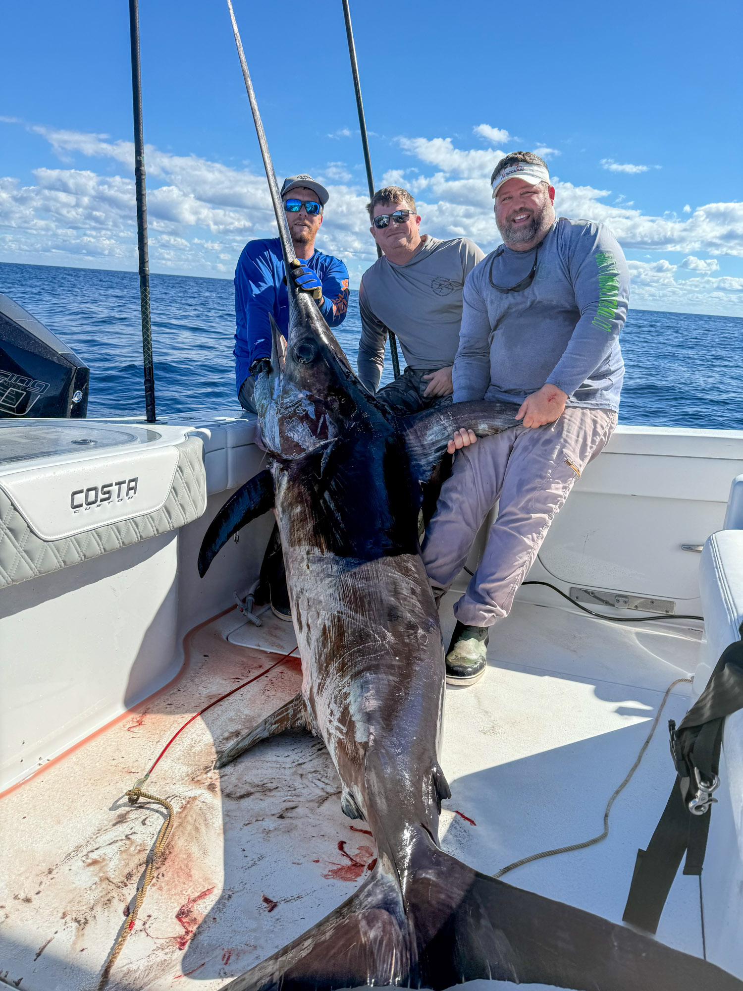 Swordfish in a boat with three anglers.