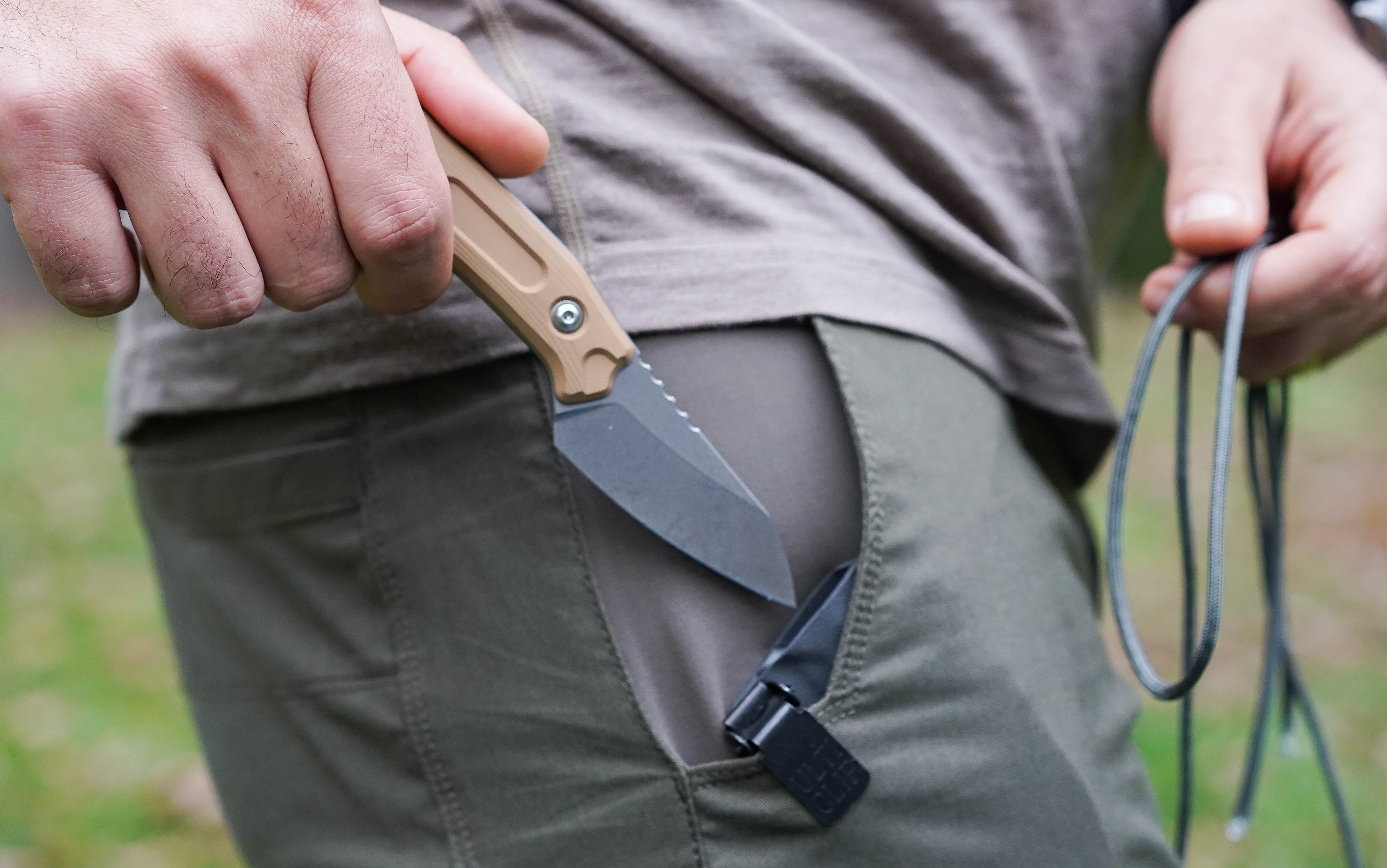 A man pulls a fixed blade knife out of a pocket sheath.