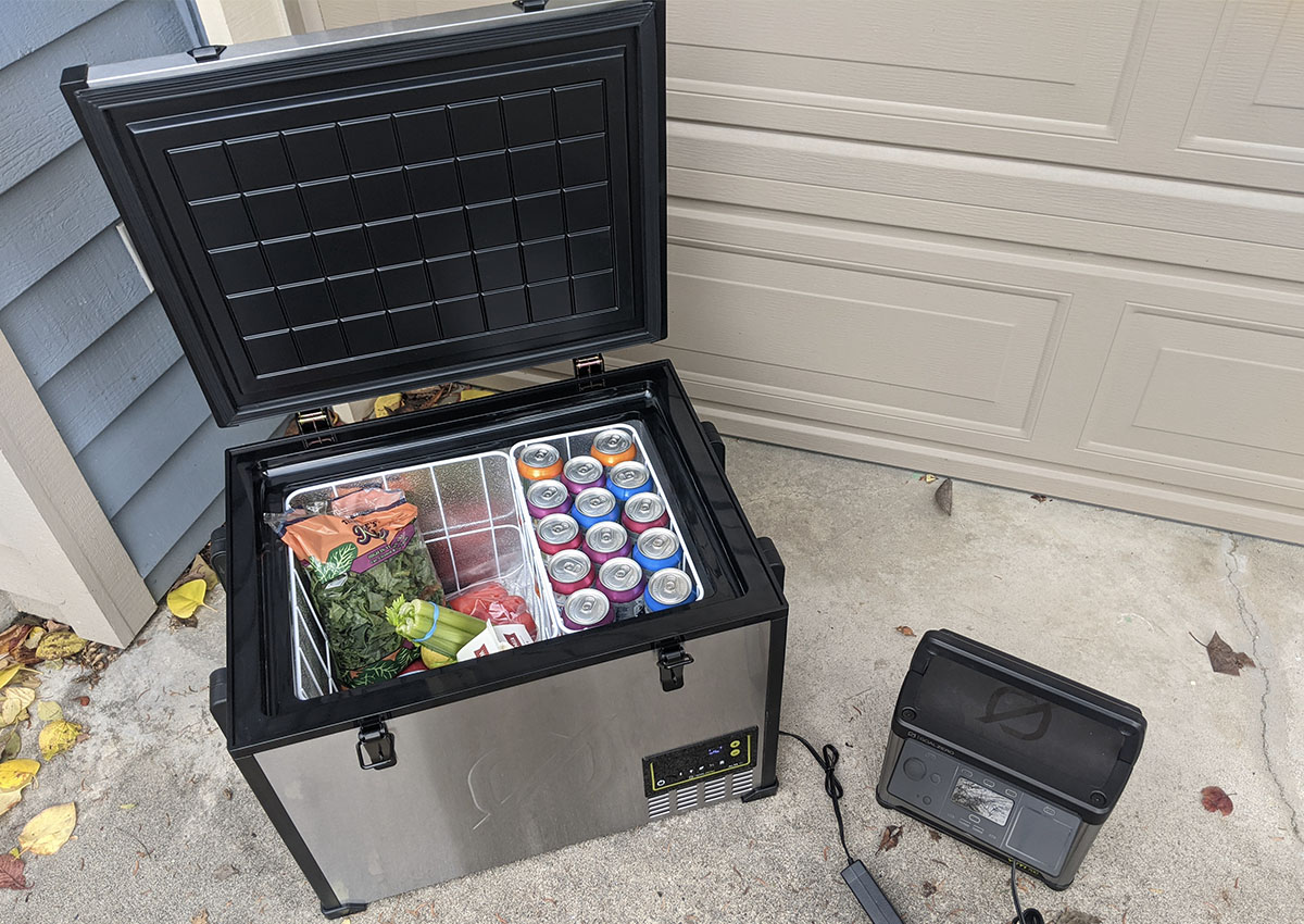 open electric cooler with produce and cans inside next to a portable power station