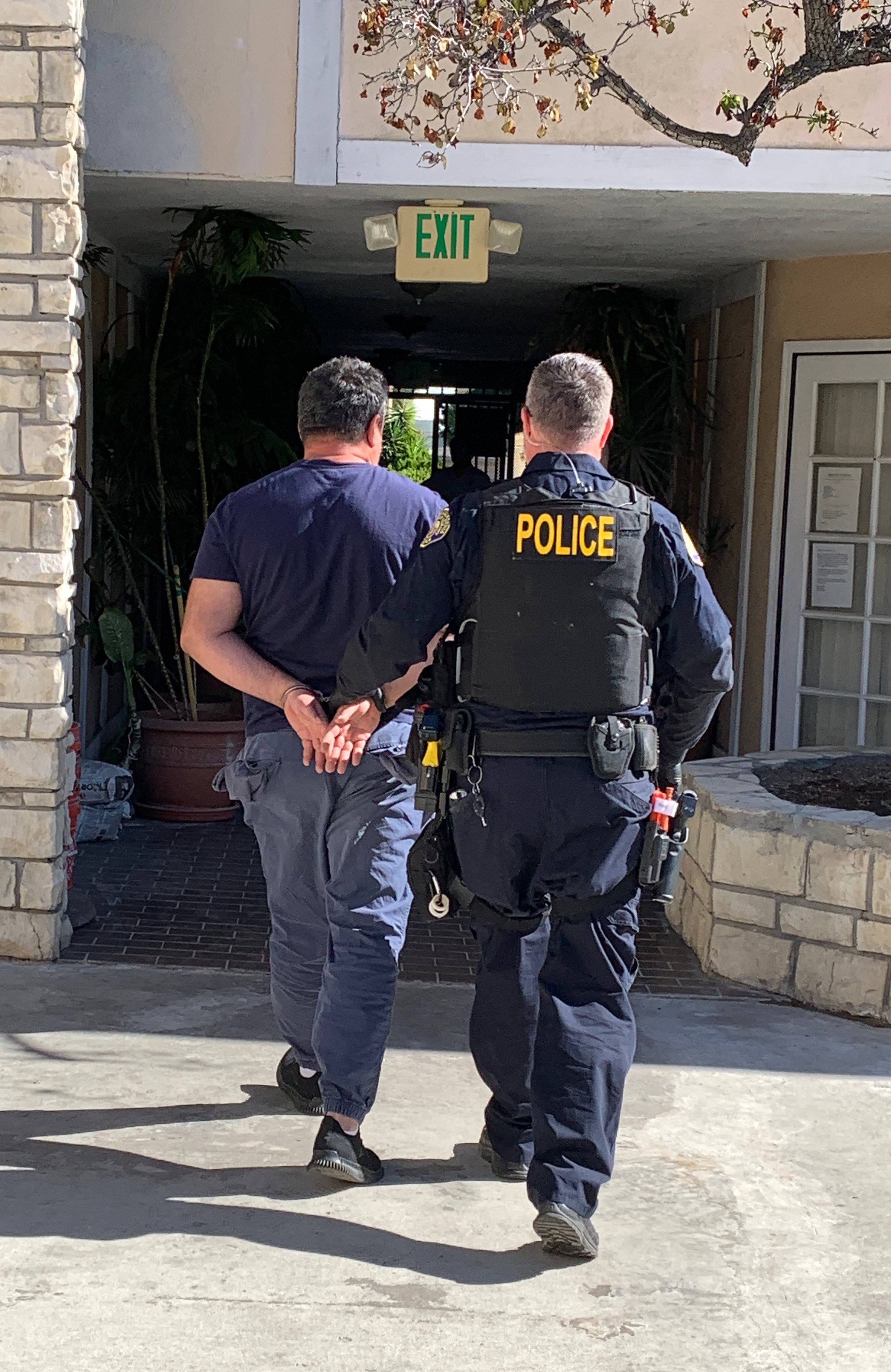 A police officer escorts a suspect who conspired to use a bear suit to defraud insurance companies.