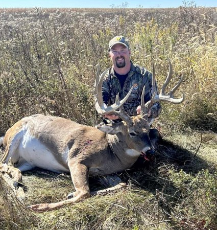 A deer hunter with a big Illinois buck in CRP grass.