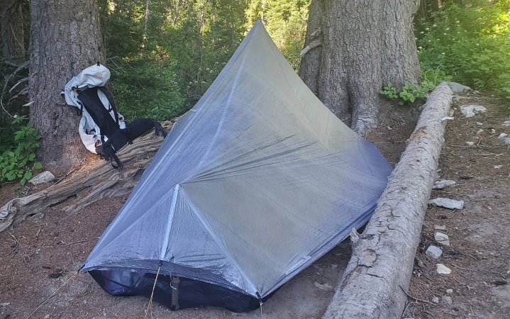  UL tent set up next to a log and a backpack in the woods