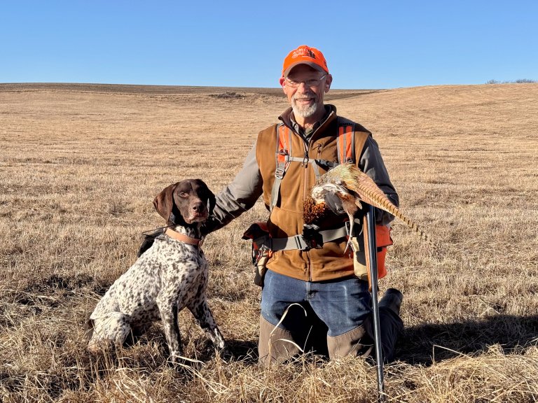 A hunter with a rooster and his dog.