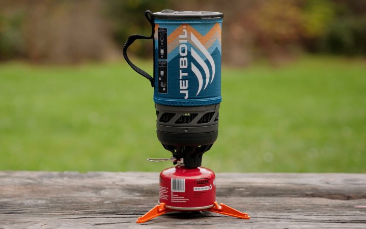  JetBoil Flash with a gas canister sitting on a picnic table with a grassy field in the background