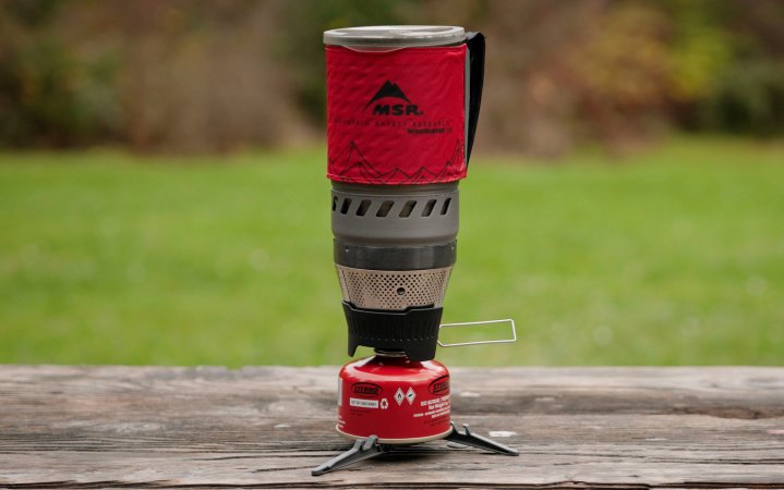  MSR Windburner with a gas canister sitting on a picnic table with a grassy field in the background