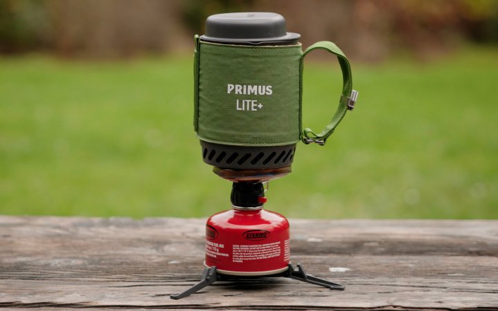  Primus Lite Plus attached to a fuel canister sitting on a picnic table with a grassy field in the background