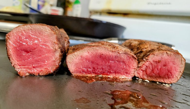 Venison backstraps sliced open to show a perfect exterior sear and a rare center.