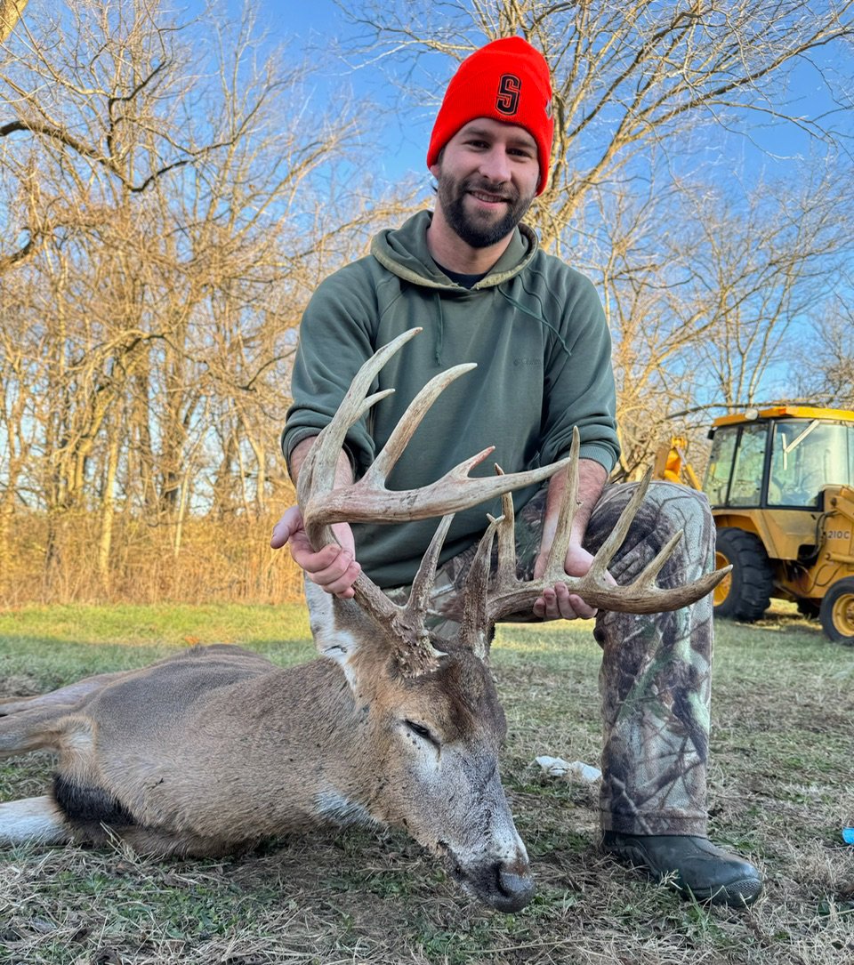 Ethan Bruce kneels beside a nice buck.