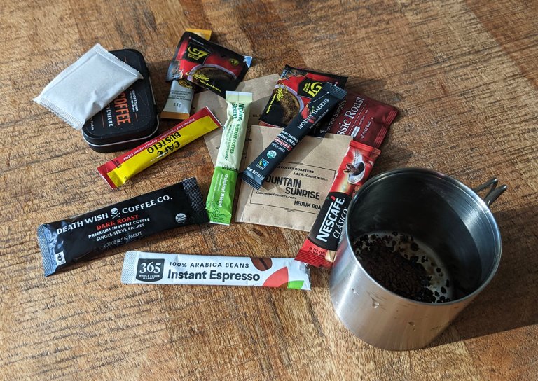 packets of instant coffee piled up on each other next to a coffee mug