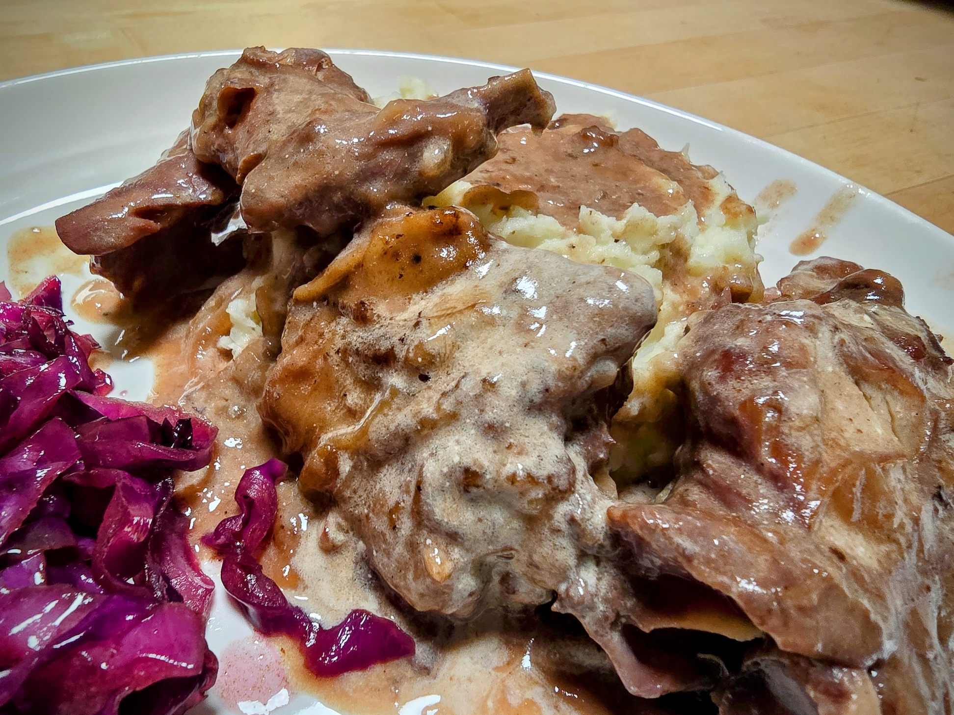 A close-up of rabbit pieces smothered in gravy over top of mashed potatoes.