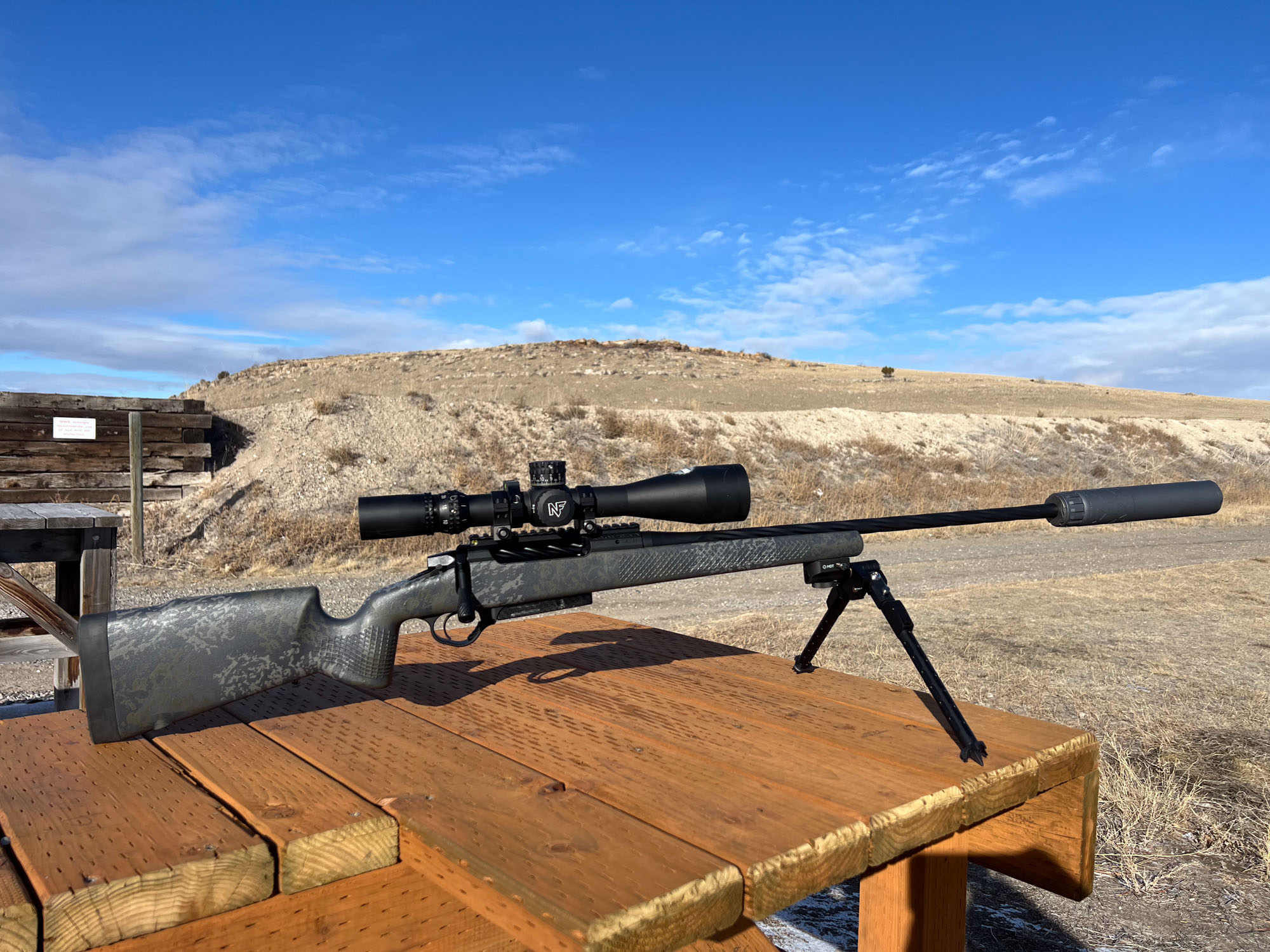 A suppressed rifle resting on a shooting bench, chambered in 7 BC.