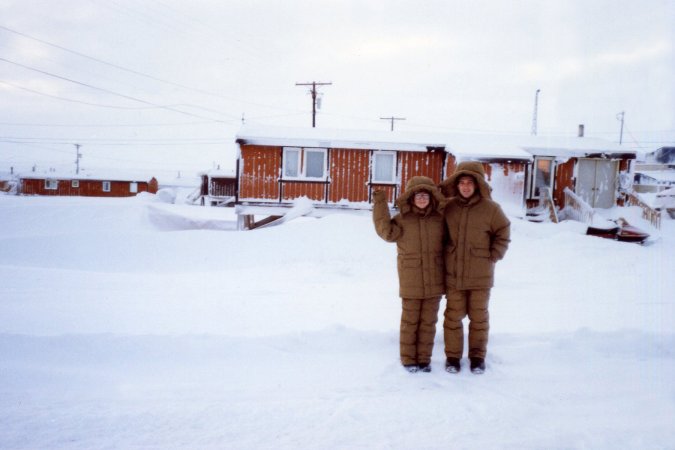 A couple in brown parkas stand in Point Lay, Alaska.