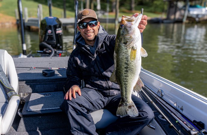 A man holds up a nice bass while wearing a winter jacket in a bass boat.