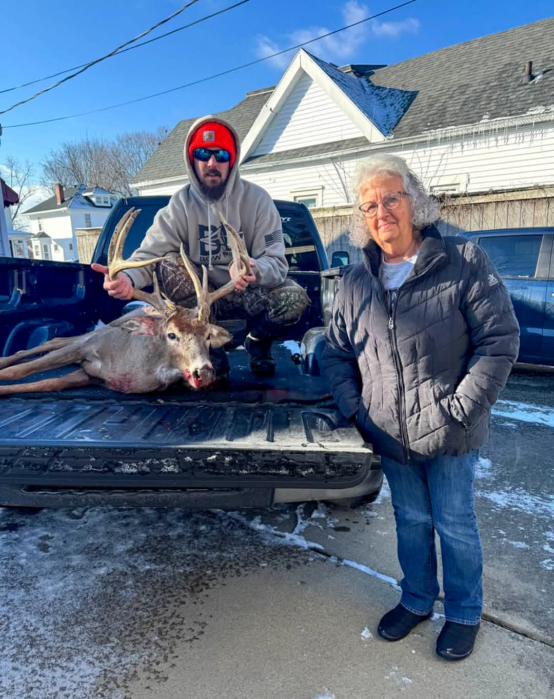 A hunter with his buck beside his grandmother.