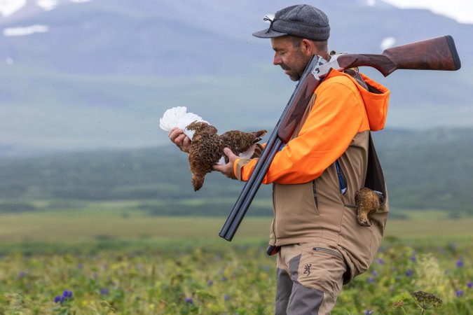 A hunter with a new Browning 825 field on his shoulder examines a ptarmigan.