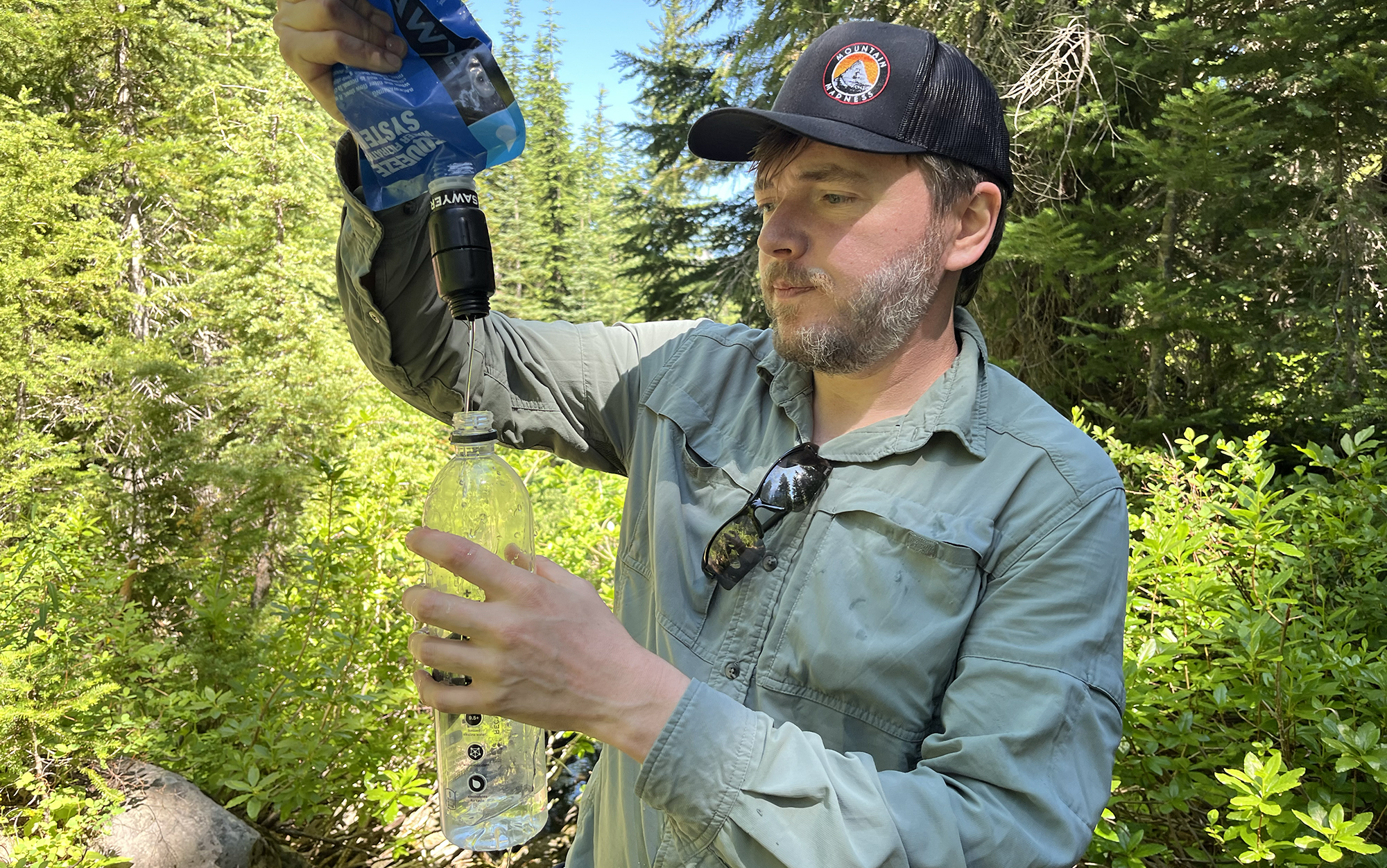 man squeezing water from a filter into a plastic water bottle