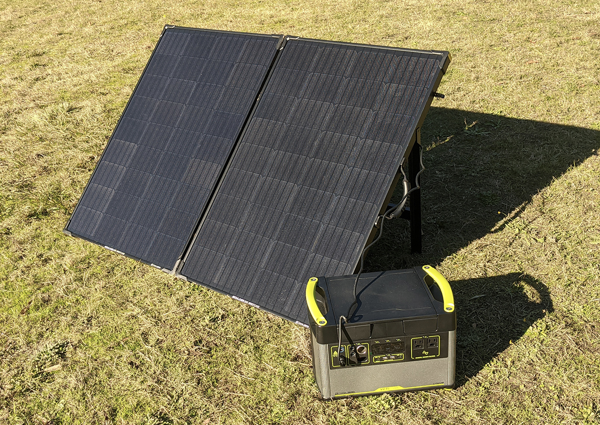 A Goal Zero power station and solar panel sitting on a grassy field in full sun