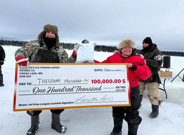 An ice fisherman holds up a $100,000 check.