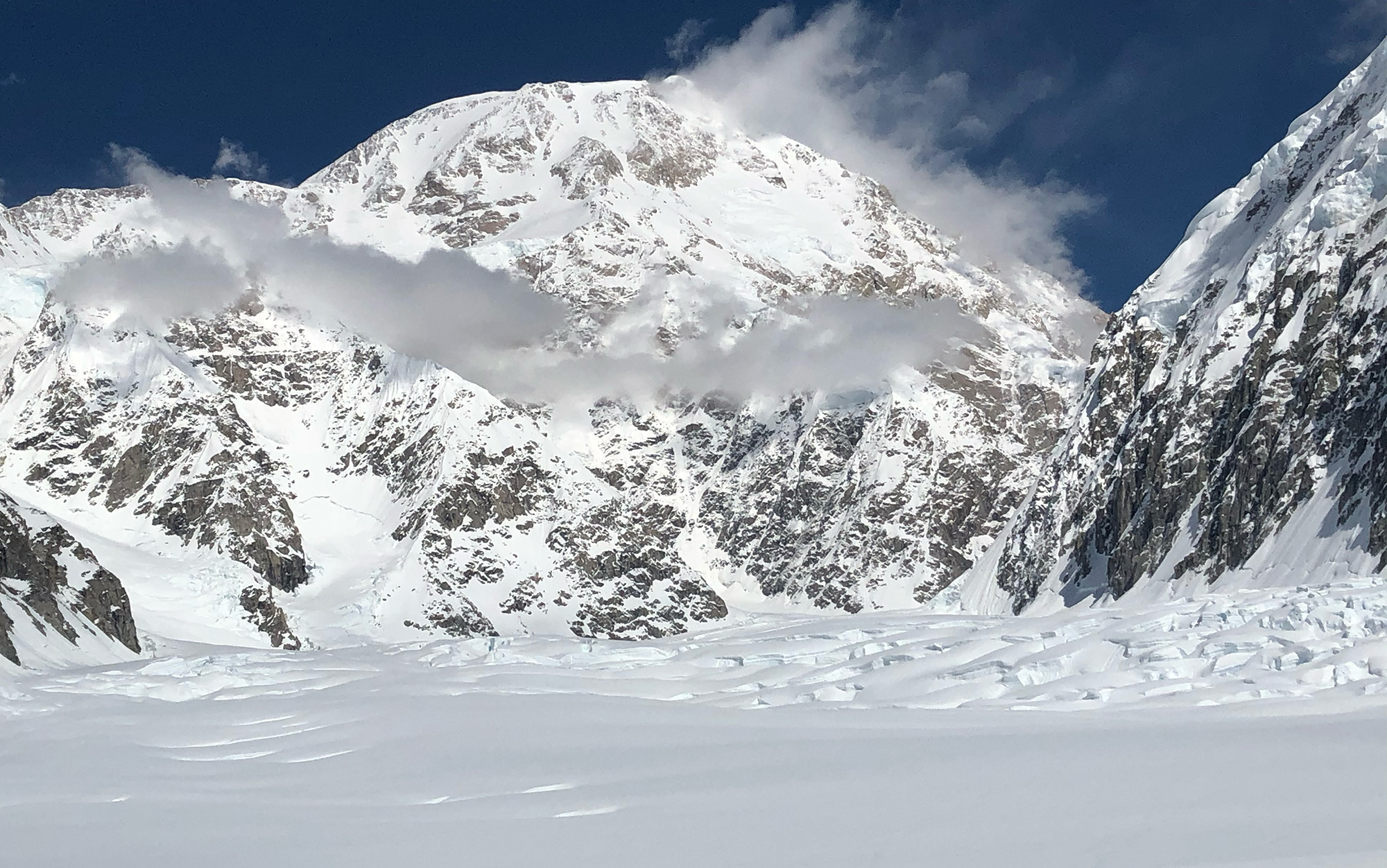 A mountain top peaks out of a glacier field.